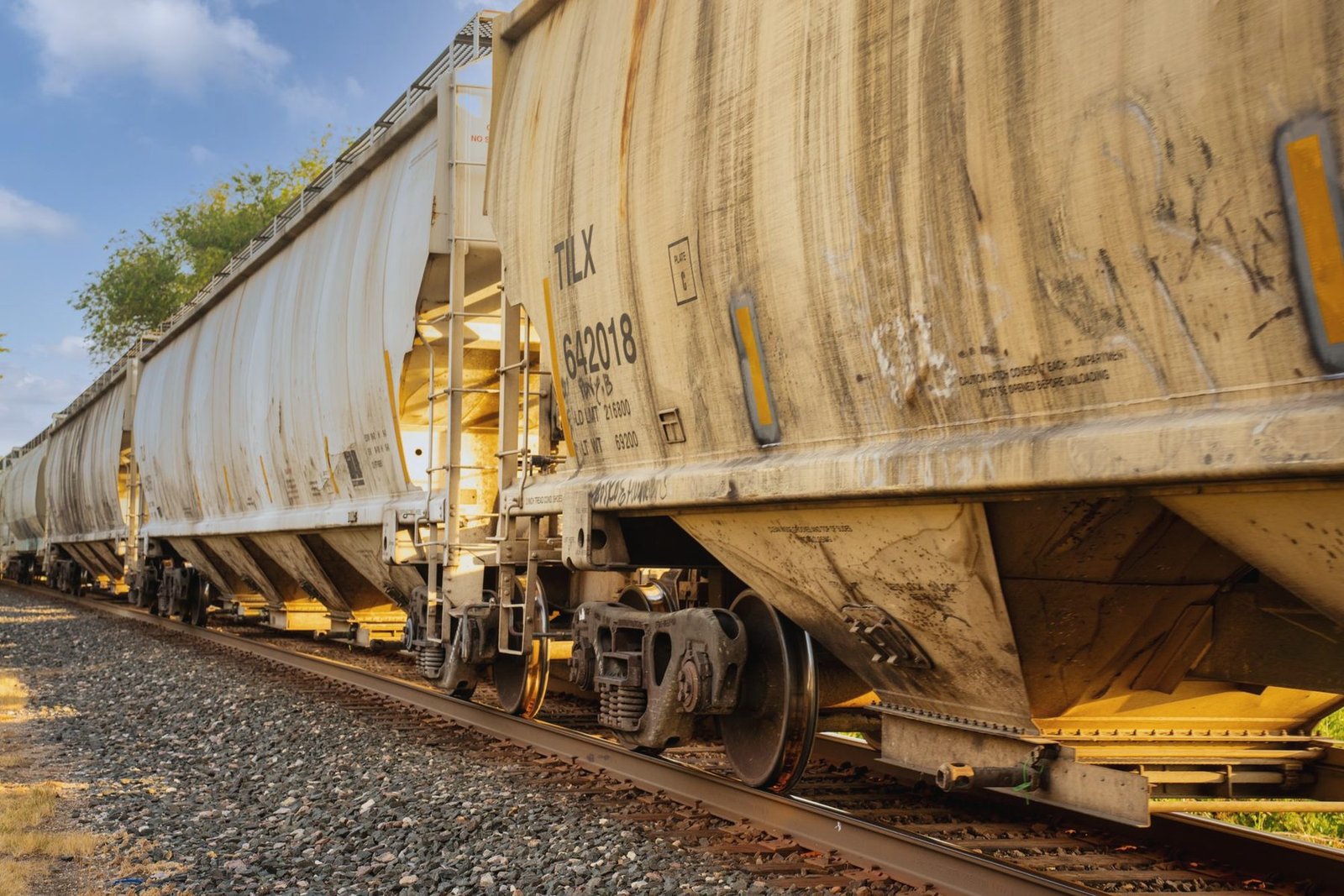 Weathered covered hopper cars with discharge gates visible underneath