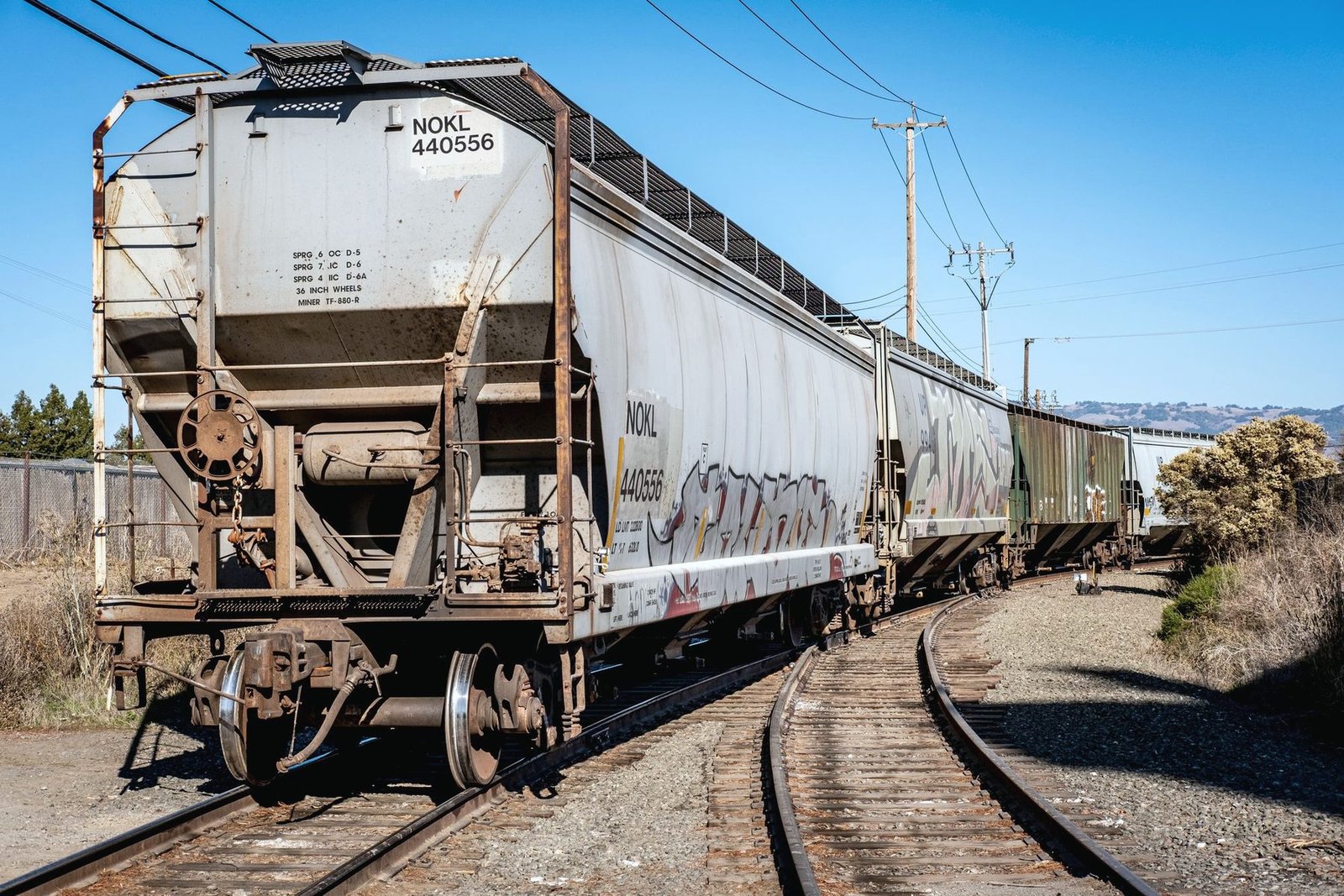 The end of a covered hopper car on a curving track under a clear sky