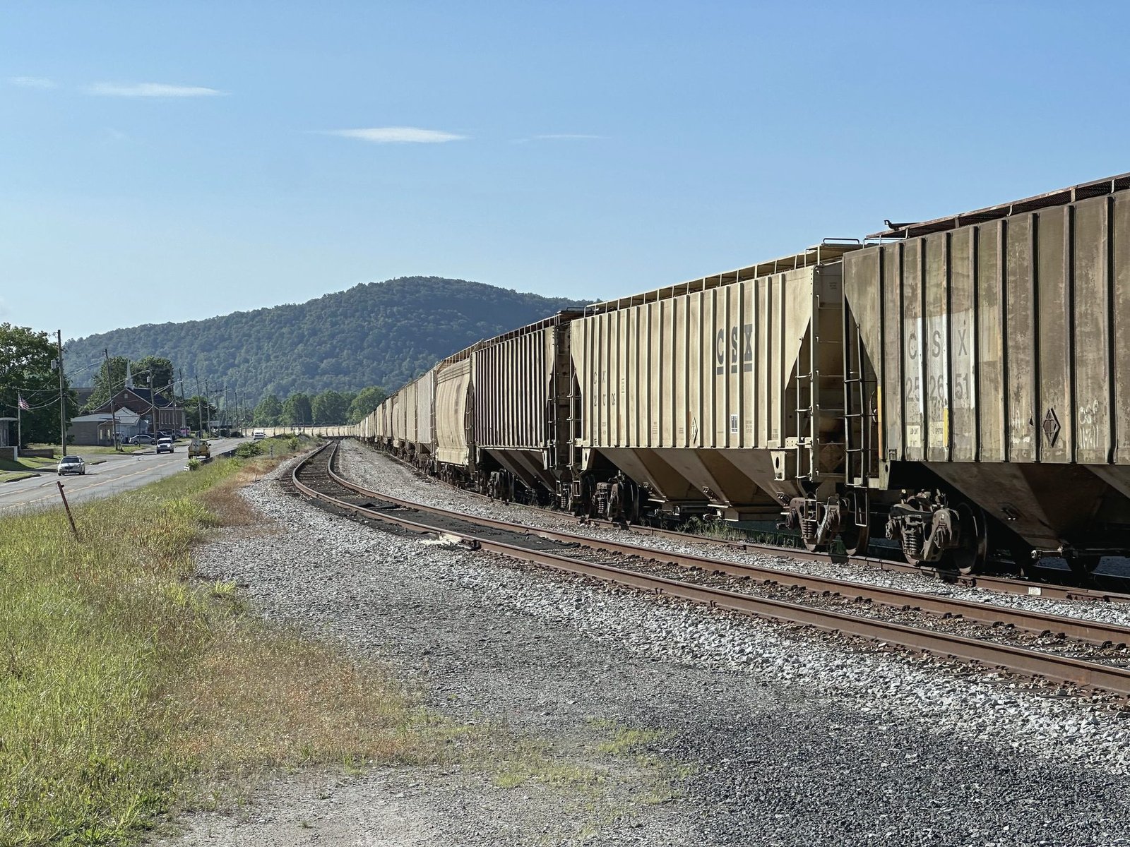 Covered hopper cars parked on a siding beside a gravel road